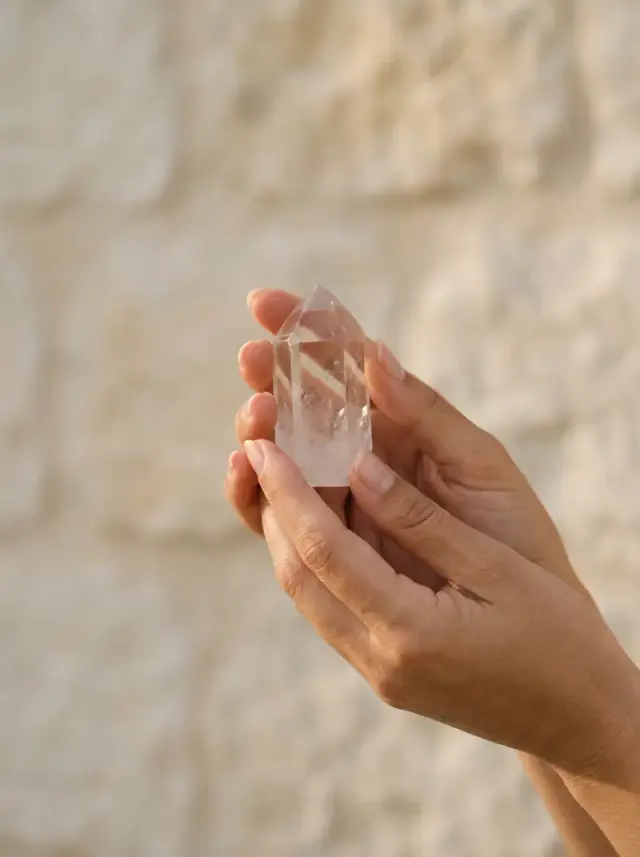 Deux mains tenant un cristal de roche dans la lumière